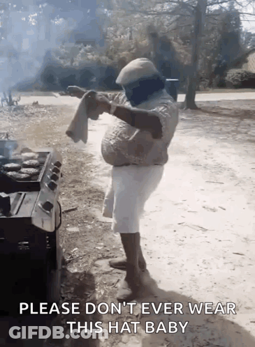 A Man Is Standing In Front Of A Grill Holding A Towel And Says Please Don 'T Ever Wear This Hat Baby GIF