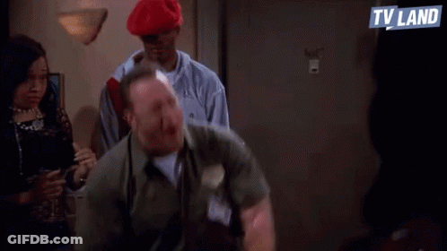 A Man Is Standing In Front Of A Group Of People And Shouting . GIF