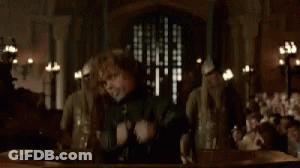 A Man Is Standing In Front Of A Group Of People Holding A Sword . GIF