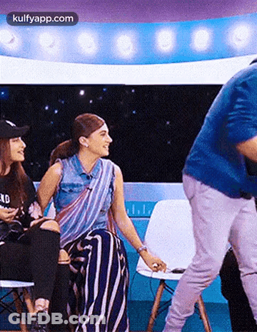 A Man Is Standing In Front Of A Group Of Women Sitting In Chairs On A Stage . GIF