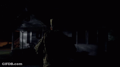 A Man Is Standing In Front Of A House That Has Christmas Lights On It GIF