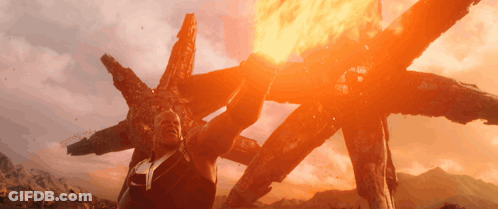 A Man Is Standing In Front Of A Huge Fire GIF
