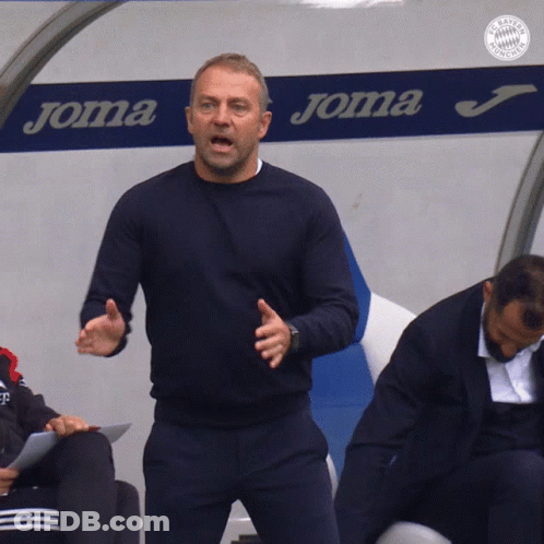 A Man Is Standing In Front Of A Joma Sign GIF