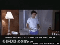 A Man Is Standing In Front Of A Lamp In A Room Holding A Remote Control . GIF