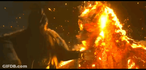 A Man Is Standing In Front Of A Large Fire GIF