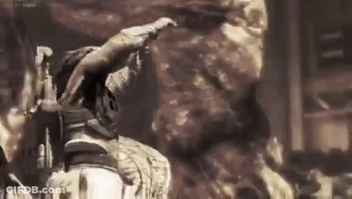 A Man Is Standing In Front Of A Large Rock In A Dark Room . GIF