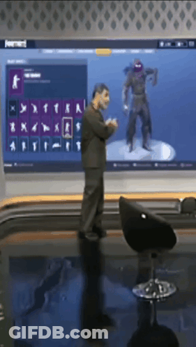 A Man Is Standing In Front Of A Large Screen With A Ninja On It GIF