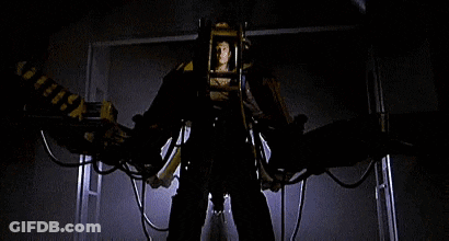 A Man Is Standing In Front Of A Machine That Looks Like A Robot With Wings . GIF