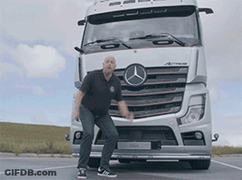 A Man Is Standing In Front Of A Mercedes Truck GIF