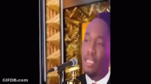 A Man Is Standing In Front Of A Microphone And Talking Into It . GIF