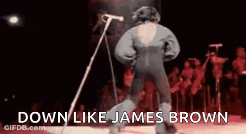 A Man Is Standing In Front Of A Microphone On A Stage And Singing . GIF