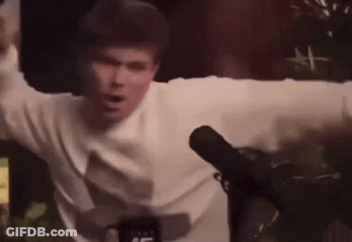 A Man Is Standing In Front Of A Microphone With His Arms Outstretched GIF