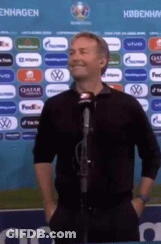 A Man Is Standing In Front Of A Microphone With His Hands In His Pockets . GIF