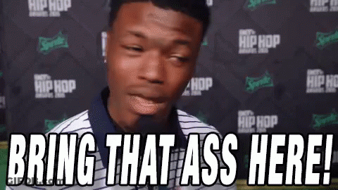 A Man Is Standing In Front Of A Microphone With The Words `` Bring That Ass Here '' . GIF