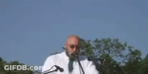 A Man Is Standing In Front Of A Microphone With The Words `` Enough Is Enough '' Written On It . GIF
