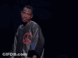A Man Is Standing In Front Of A Microphone With The Words Next Time Written On The Screen Behind Him . GIF