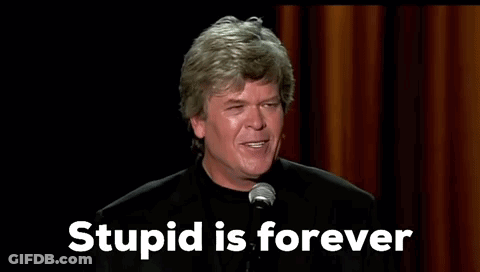 A Man Is Standing In Front Of A Microphone With The Words `` Stupid Is Forever '' Written On The Screen . GIF
