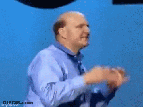 A Man Is Standing In Front Of A Microsoft Windows Logo GIF