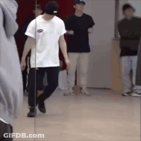 A Man Is Standing In Front Of A Mirror In A Dance Studio . GIF