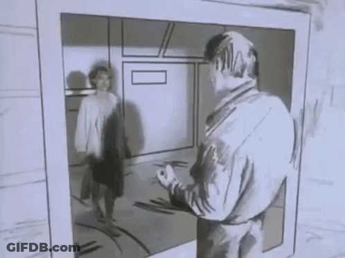 A Man Is Standing In Front Of A Mirror Looking At Himself In A Black And White Photo . GIF