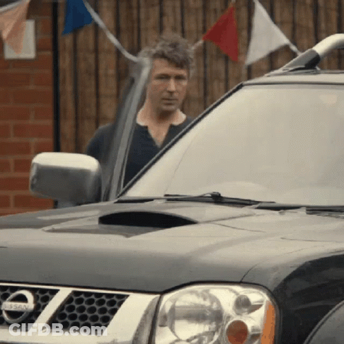 A Man Is Standing In Front Of A Nissan Car GIF