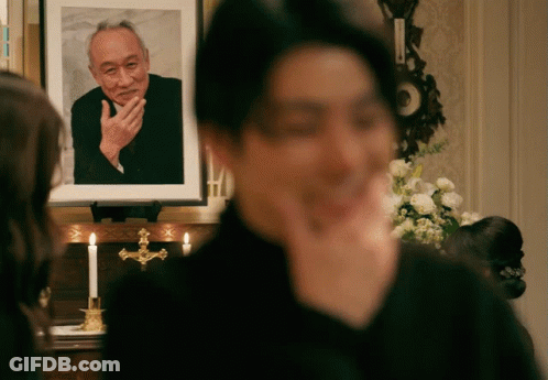 A Man Is Standing In Front Of A Picture Of A Man GIF