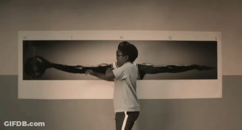 A Man Is Standing In Front Of A Picture Of A Person 'S Wings GIF