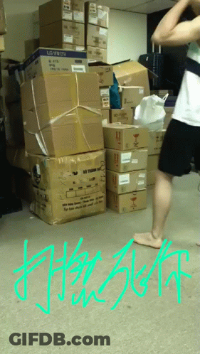 A Man Is Standing In Front Of A Pile Of Boxes With The Word Lg On Them GIF