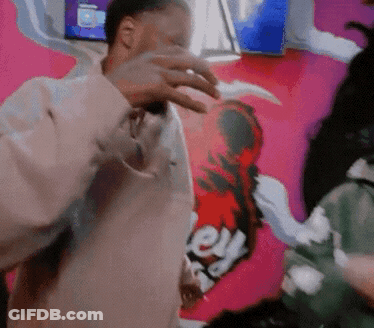 A Man Is Standing In Front Of A Pink Wall With A Sticker On It That Says Ey GIF