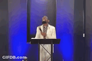 A Man Is Standing In Front Of A Podium With A Microphone And A Woman Is Standing Behind Him . GIF