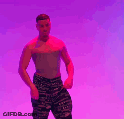 A Man Is Standing In Front Of A Purple Background With His Hands Folded . GIF