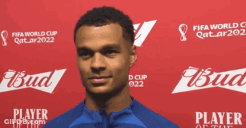 A Man Is Standing In Front Of A Red Background That Says Fifa World Cup Qatar2022 And Bud GIF
