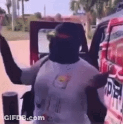 A Man Is Standing In Front Of A Red Car With His Arms Outstretched GIF
