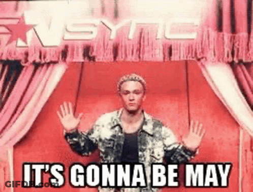 A Man Is Standing In Front Of A Red Curtain And A Sign That Says It 'S Gonna Be May GIF