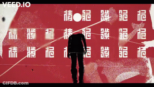 A Man Is Standing In Front Of A Red Wall With Chinese Characters And The Word Veed.io On The Bottom GIF
