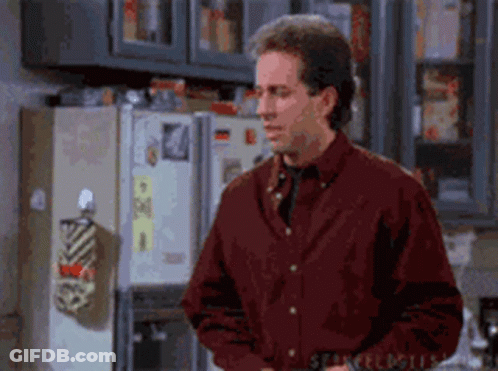 A Man Is Standing In Front Of A Refrigerator In A Kitchen . GIF