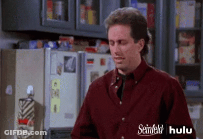 A Man Is Standing In Front Of A Refrigerator In A Kitchen . GIF