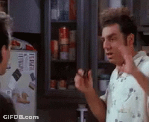 A Man Is Standing In Front Of A Refrigerator Talking To Another Man In A Kitchen . GIF