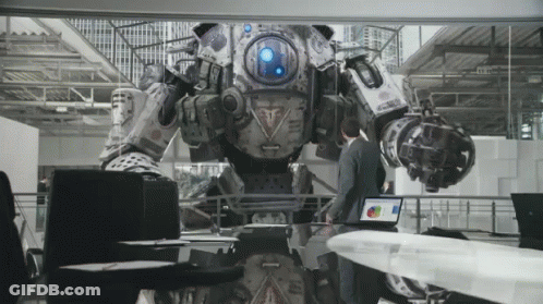 A Man Is Standing In Front Of A Robot That Has A Blue Light On The Front GIF