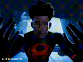 A Man Is Standing In Front Of A Screen With His Arms Outstretched In A Dark Room . GIF