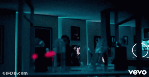 A Man Is Standing In Front Of A Shelf Full Of Trophies And A Sign That Says Vevo On It GIF
