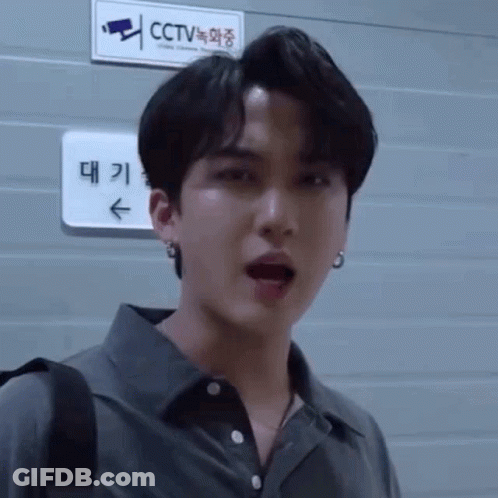 A Man Is Standing In Front Of A Sign That Says Cctv On It . GIF