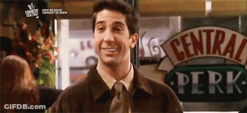 A Man Is Standing In Front Of A Sign That Says Central Perk GIF