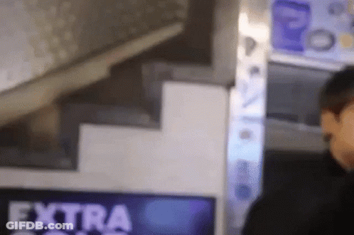 A Man Is Standing In Front Of A Sign That Says Extra On It . GIF