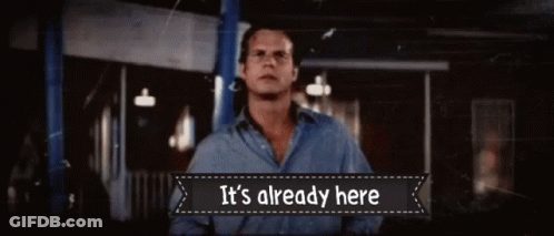 A Man Is Standing In Front Of A Sign That Says It 'S Already Here GIF