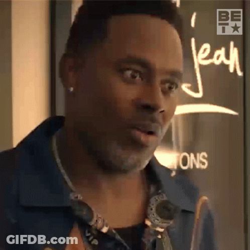 A Man Is Standing In Front Of A Sign That Says Jean On It GIF