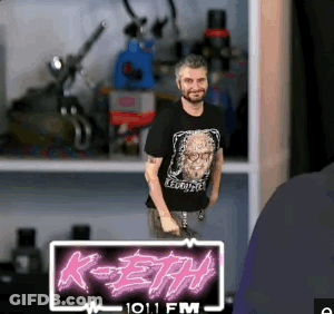 A Man Is Standing In Front Of A Sign That Says K-Eth On It GIF