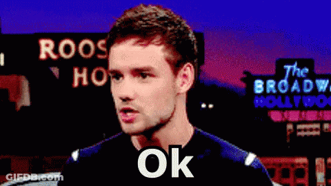 A Man Is Standing In Front Of A Sign That Says Roos Hollywood GIF