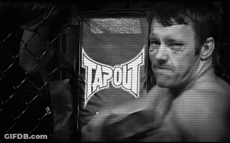 A Man Is Standing In Front Of A Sign That Says Tapout On It . GIF