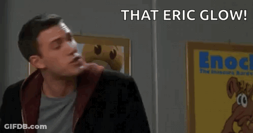 A Man Is Standing In Front Of A Sign That Says " That Eric Glow ! Survey Says ! " GIF